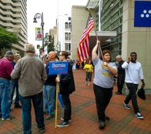 Woman marches with American flag near Sanders supporters